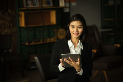 Portrait of smiling young businesswoman using digital tablet in office