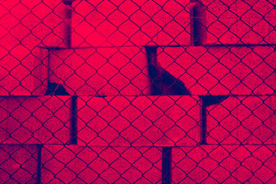 Full frame shot of chainlink fence against wall