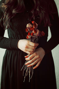 Conceptual young girl in black vintage dress and dried flowers