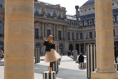 Woman standing by colonnes de buren les deux plateaux in paris 