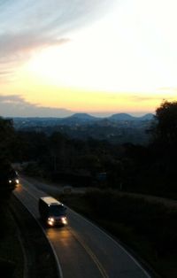 Cars on road against sky at sunset