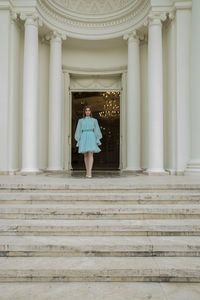 Rear view of woman standing by staircase of building