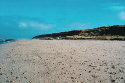 Scenic view of beach against blue sky