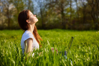 Side view of young woman sitting on field