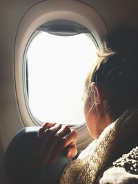 Close-up of girl looking through airplane window