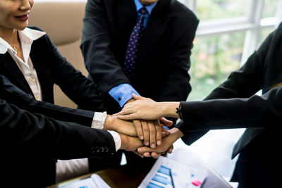 Midsection of business people stacking hands at office