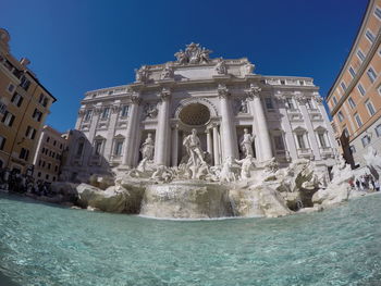 Fountain in city against clear blue sky
