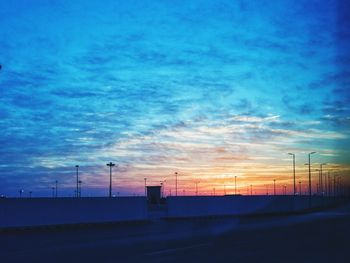 Silhouette of factory against sky during sunset