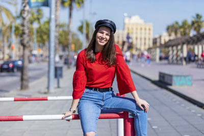 Smiling teenage girl wearing red top in city during sunny day