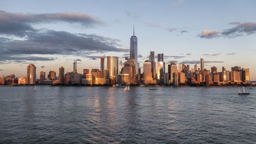 Sea and buildings in city against cloudy sky