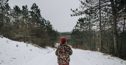 Rear view of man standing on snow covered landscape