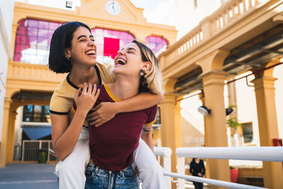 Laughing lesbian couple walking against building