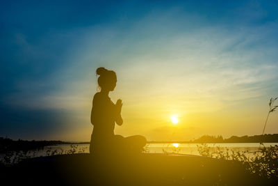 Silhouette man standing by sea against sky during sunset