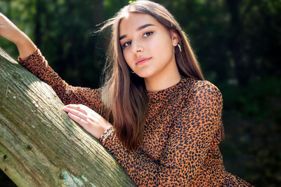 Emotional girl teenager with long hair hairstyle braids in a green shirt sits on a bench in the park