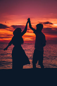 Silhouette woman standing on beach during sunset