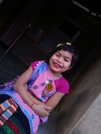 Portrait of smiling girl wearing traditional clothing against house