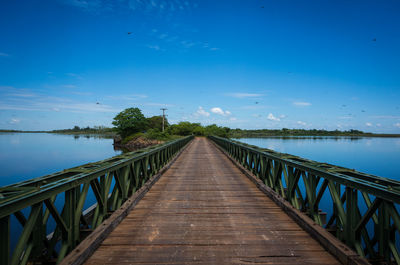 Pier over lake against blue sky