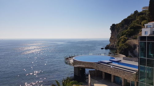 High angle view of swimming pool by sea against clear sky