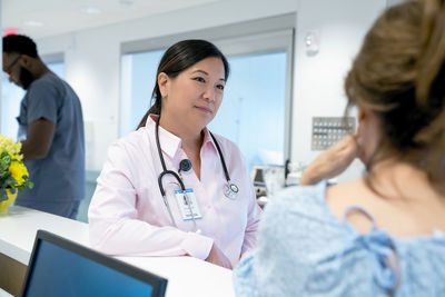 Doctor looking at female colleague with male coworker in background