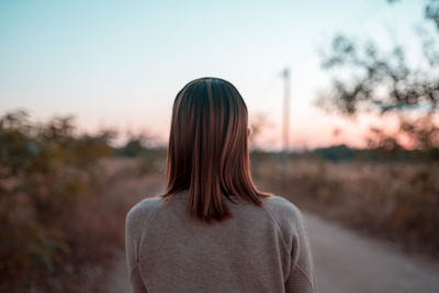 Rear view of woman standing against sky during sunset