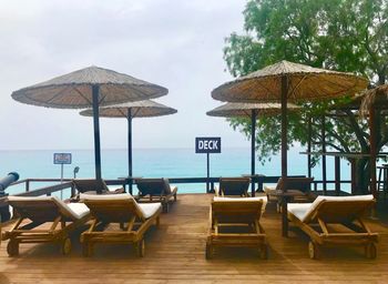 Empty chairs and tables on beach against sky