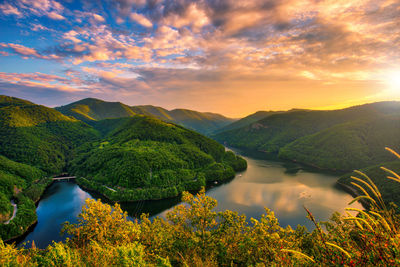 Scenic view of river and mountains against sky at sunset