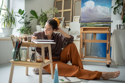 Side view of woman sitting on chair at home