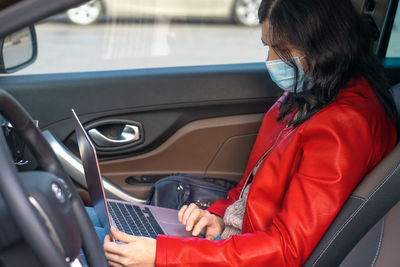 Rear view of woman using mobile phone while sitting in car