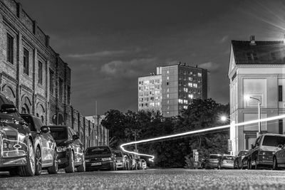 Cars on street by buildings against sky in city at night