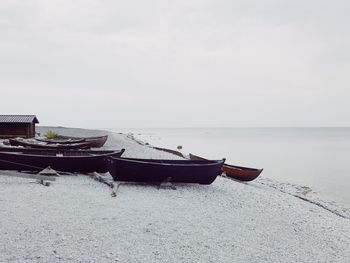 Boat moored on beach against sky