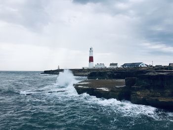 Lighthouse by sea against sky