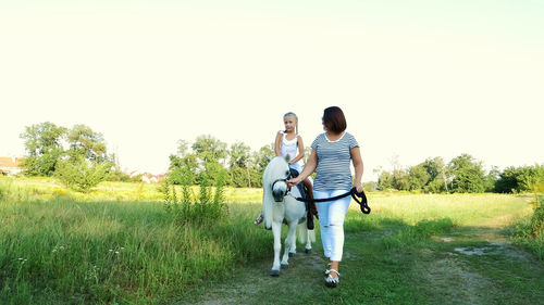 Rear view of couple with dog on field