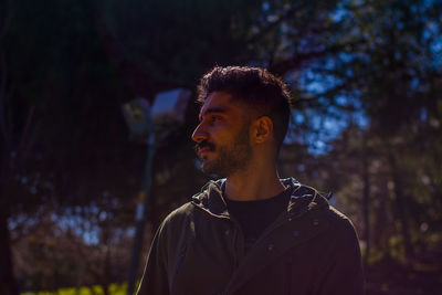 Thoughtful young man standing against trees