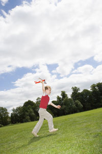 Boy playing on field against sky