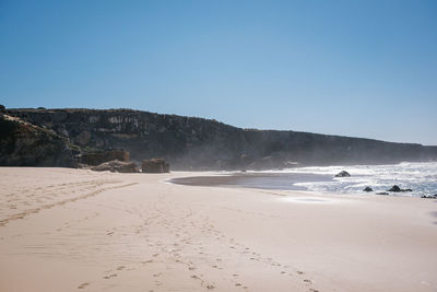 Scenic view of beach against clear blue sky