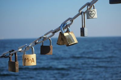 Close-up of padlocks on pole against sea