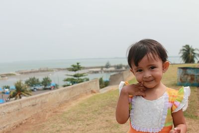 Portrait of cute girl standing on land against sky