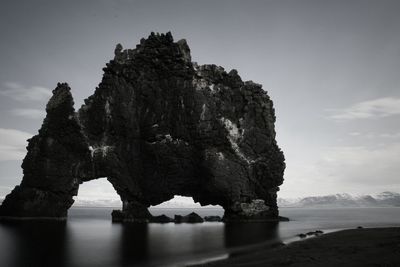 Rock formation by sea against sky