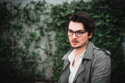 Portrait of young man standing against plants