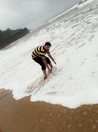 Full length of man skateboarding at beach against sky