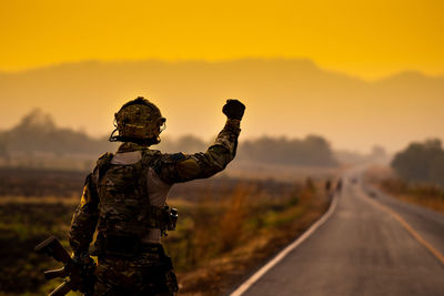 Army soldier with hand raised standing on road