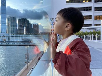 Side view of boy blowing bubbles in city