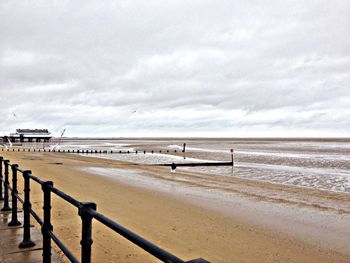 Pier on sea against cloudy sky