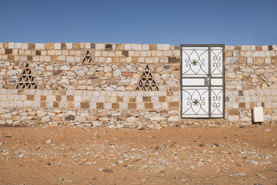 Graffiti on wall of old building against clear blue sky