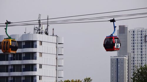 Low angle view of overhead cable cars against buildings