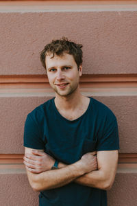 Portrait of young man standing against wall