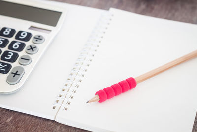 High angle view of pencil and book with calculator on table