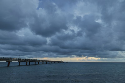 Bridge over sea against cloudy sky