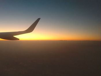 Airplane on runway against clear sky during sunset