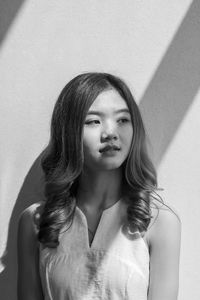 Beautiful young woman standing against wall